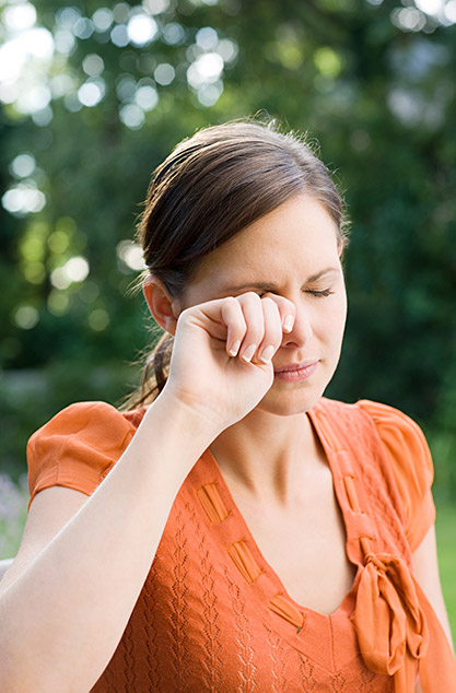 woman with allergies rubbing her eye